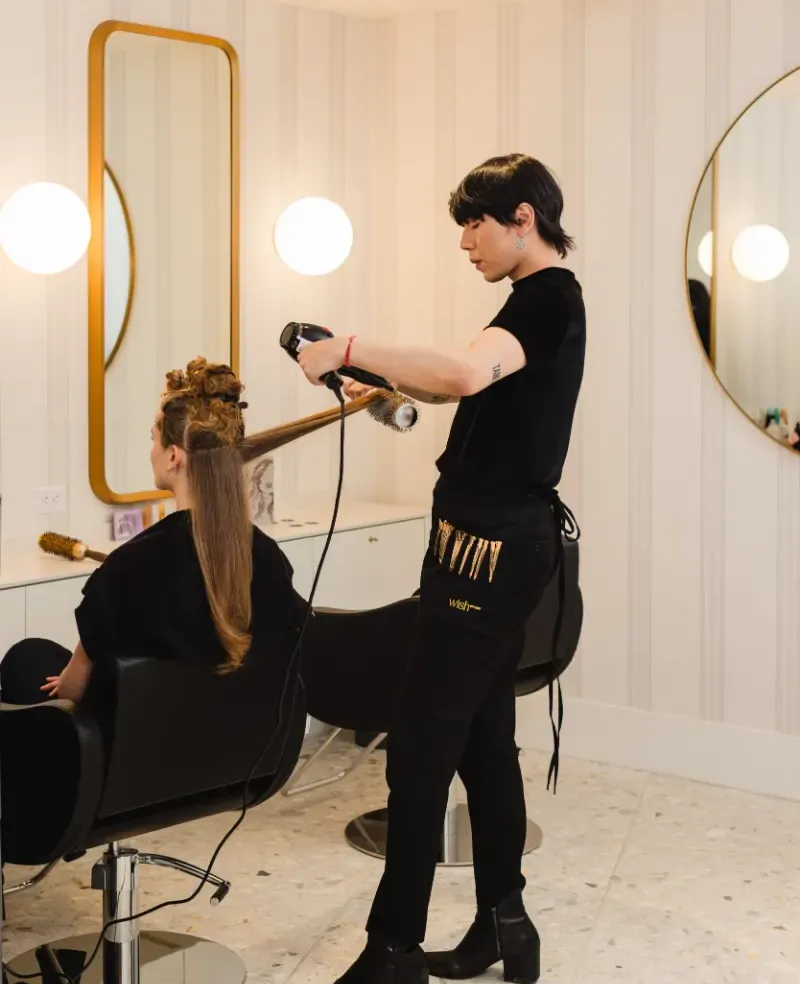 Stylist blow-drying a client with a round brush at Wish Dry Bar in downtown Vancouver