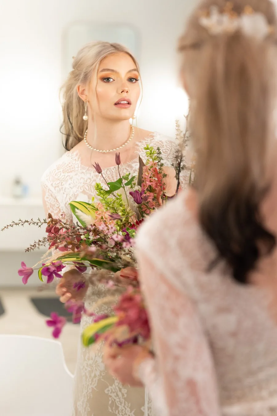 Bride with a half-up style and pearl jewellery holding her bouquet
