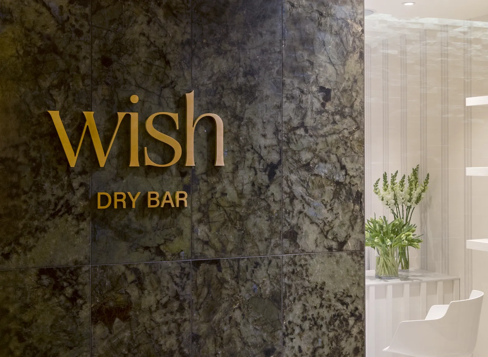 Gold Wish Dry Bar sign on the marble wall at the Vancouver salon entrance