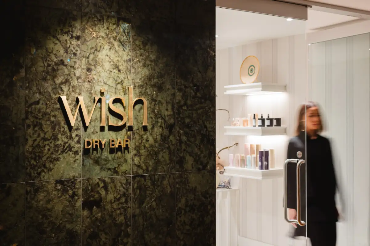 Gold Wish Dry Bar sign on the marble wall at the downtown Vancouver salon entrance